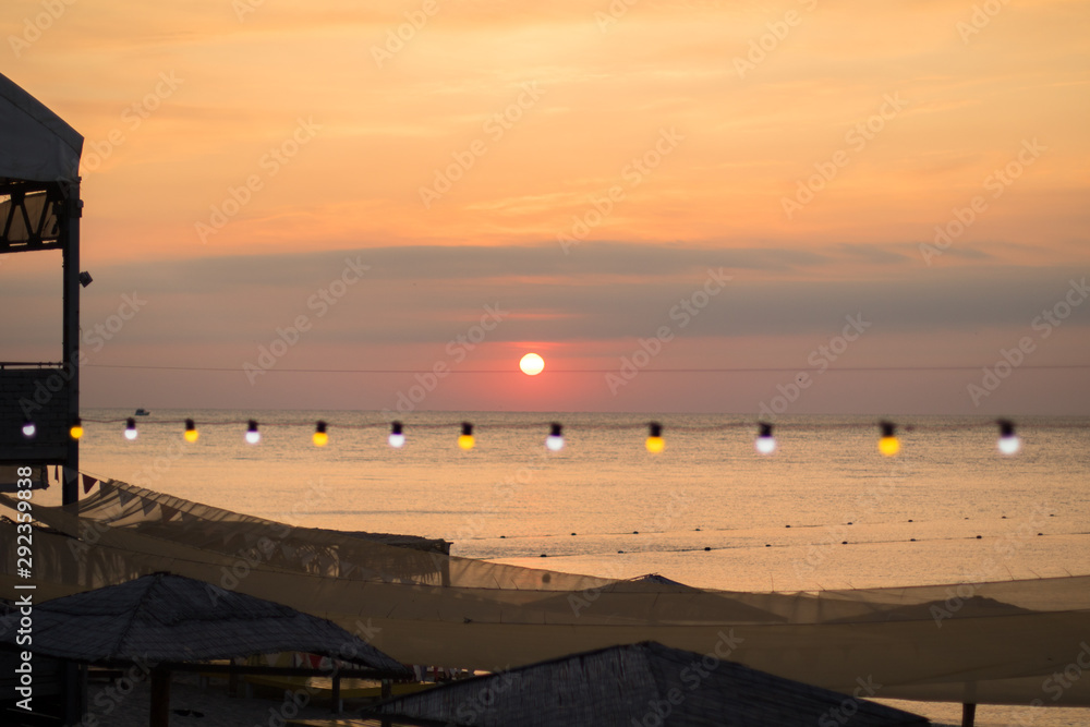 red sunrise on the sea, lamp garland on the beach