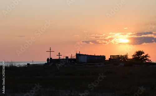 hermit monk house and crosses on the beach on the island, red sunset on the sea