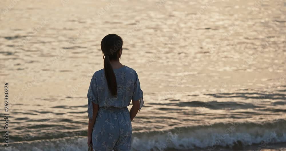 Woman stand on the beach and enjoy the view of the sea at sunset time Woman stand on the beach and enjoy the view of the sea at sunset time