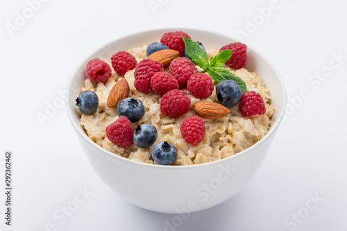 Oatmeal with raspberries, almonds and blueberries and mint on white background NOT isolated