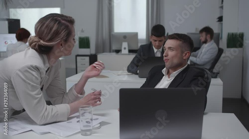 Collegues flirt and talk with each other at work.