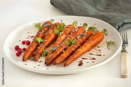 Baked organic carrots with honey, parsley, cheese and flax, pumpkin, sunflower seed on plarte. Organic vegan food.