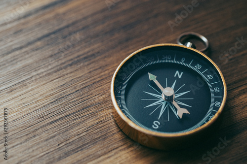 One gold compass on top of a wooden desk