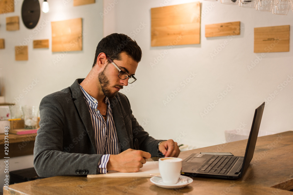 Young businessman is writing in his notebook in a pub Young businessman is writing in his notebook in a pub