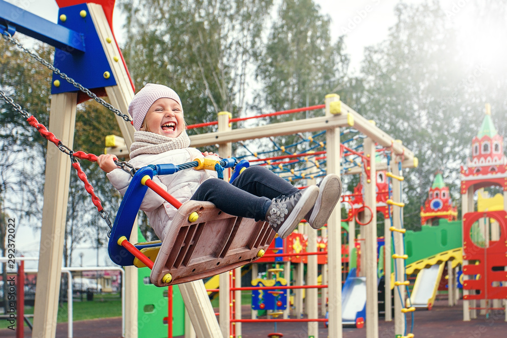 Happy child swinging on playground.