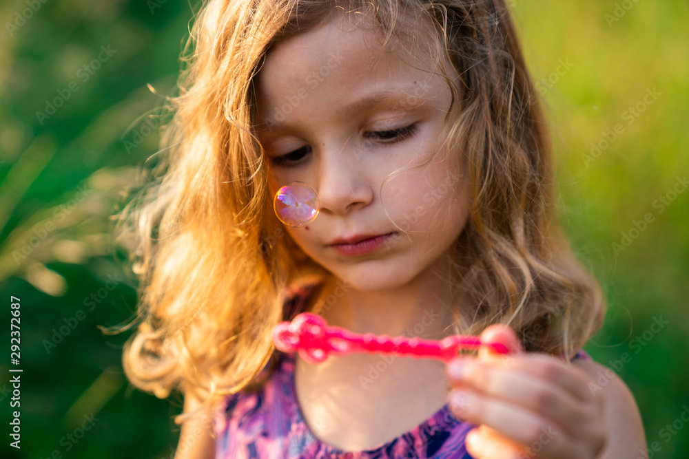 Young girl with curly hair blowing a bubble outdoors Young girl with curly hair blowing a bubble outdoors
