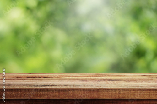 Blurred abstract green and wooden table background.