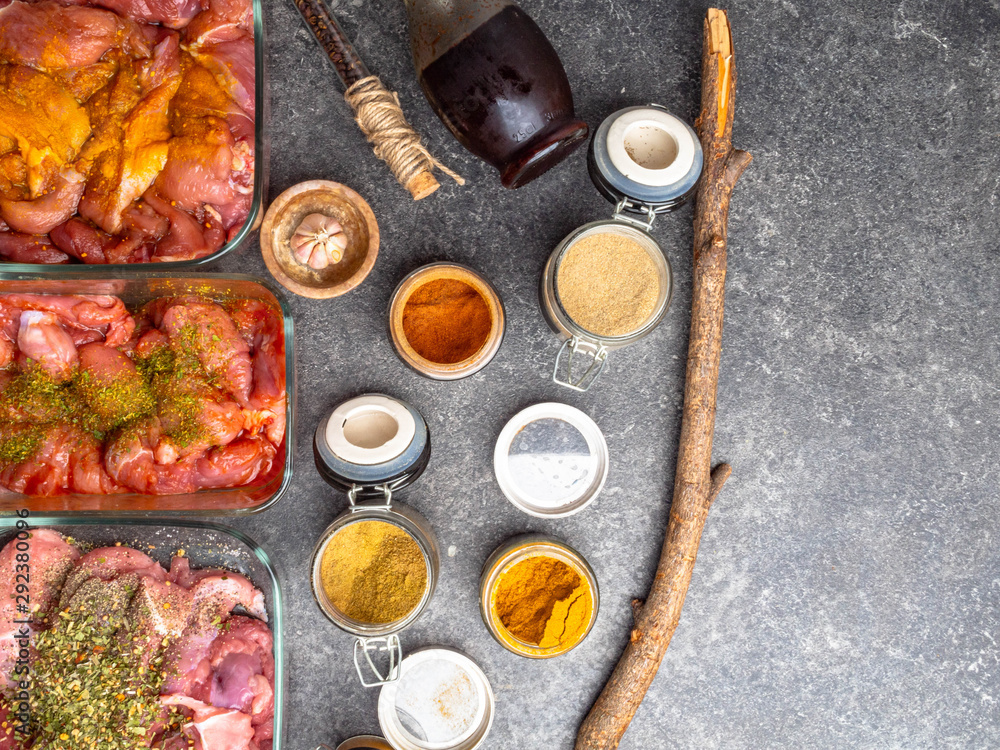 different pickled meat in glass bowls, and jars with spices ad herbs as curcuma,cardamon, rosemary, black pepper, soy and pomegranate sauce on grey background different pickled meat in glass bowls, and jars with spices ad herbs as curcuma,cardamon, rosemary, black pepper, soy and pomegranate sauce on grey background