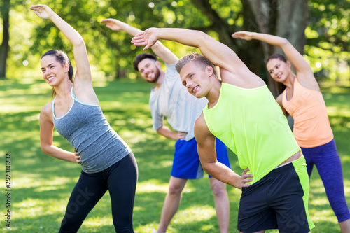 fitness  sport and healthy lifestyle concept - group of happy people exercising at summer park