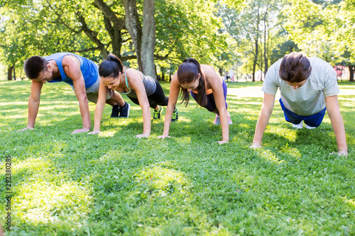 fitness, sport and healthy lifestyle concept - group of people doing push-ups or plank exercise at summer park or boot camp
