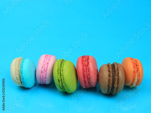 Colorful french macarons (macaroons) cake,  delicious sweet dessert on blue background with copyspace, food background concept.