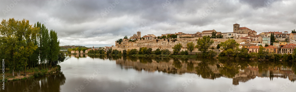 Panorama view of the reflection of the cityscape on the rocky cliff shore of the Douro River of Zamora, Spain.