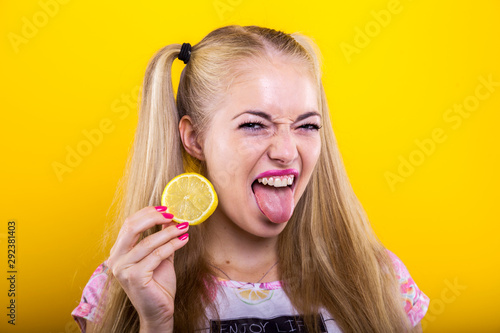 Fotografie Naughty blonde with lemon slice makes a sour face facial expression isolated aga