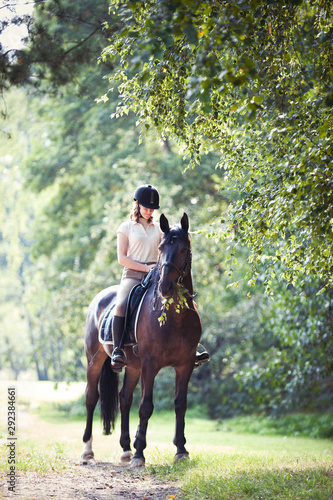 Young girl riding horseback at early morning in sunlight