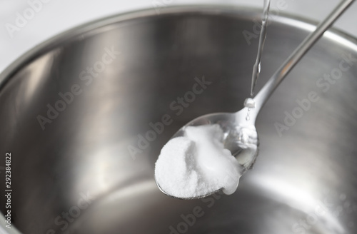 Foaming baking soda slaked with vinegar in a spoon over a metal dish