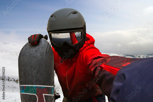 a snowboarder leaning on a board photographs himself on an outstretched hand on a camera photo
