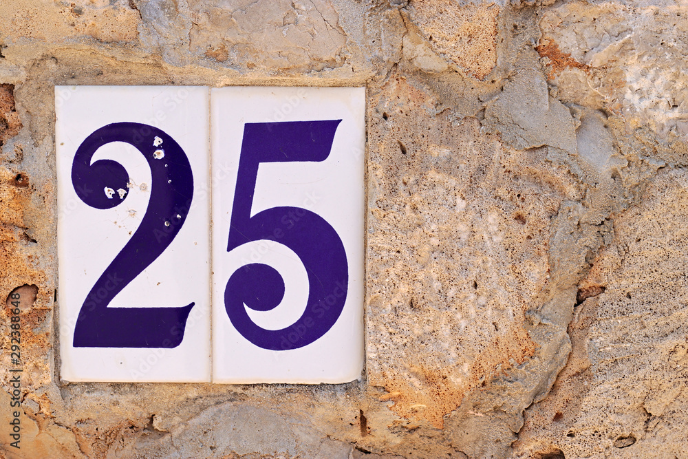 blue on white house number sign on a stone wall blue on white house number sign on a stone wall