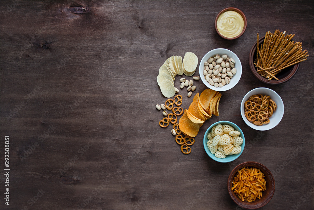 Beer with pretzels and various snacks. Beer snacks. Wood background. View from above. Place for text. Beer with pretzels and various snacks. Beer snacks. Wood background. View from above. Place for text.