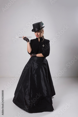 Beautiful blonde in an elegant vintage black dress, an elegant hat and a cigarette with a long mouthpiece.