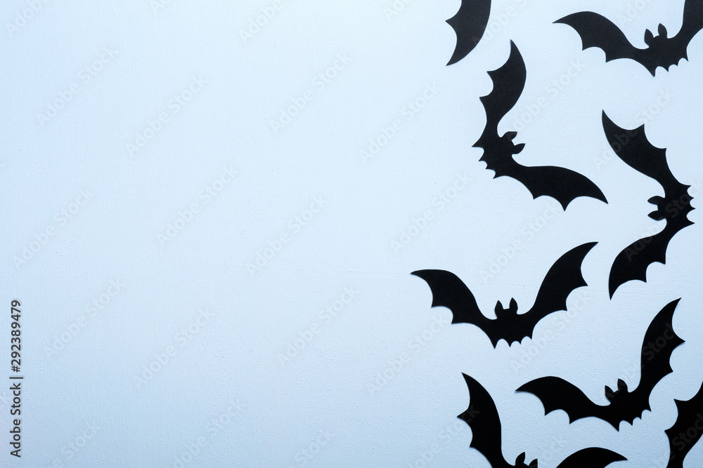 Happy halloween holiday concept. Halloween paper decorations scary bats on blue background. Halloween party greeting card mockup with copy space. Flat lay, top view, overhead.