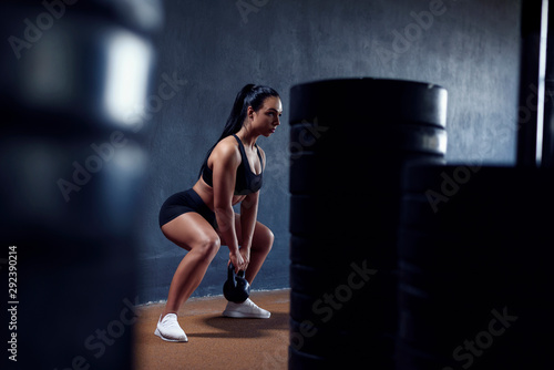 Sport active woman make training on gym with weights - squat with kettlebell. Sexy athletic girl, with black hair.