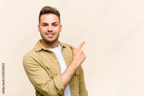 young hispanic man looking excited and surprised pointing to the side and upwards to copy space against isolated background photo