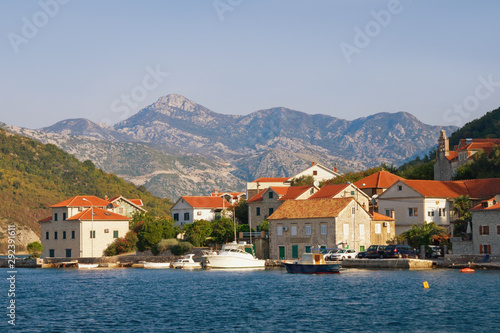 Beautiful autumn Mediterranean landscape. Small seaside village with red roofs at the foot of the mountains. Montenegro, Adriatic Sea, Bay of Kotor, Lepetane village © Olga Iljinich