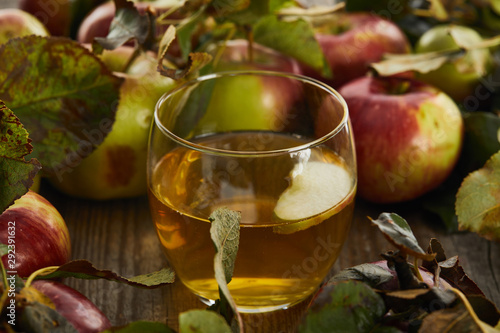 glass of fresh cider near apples on wooden surface