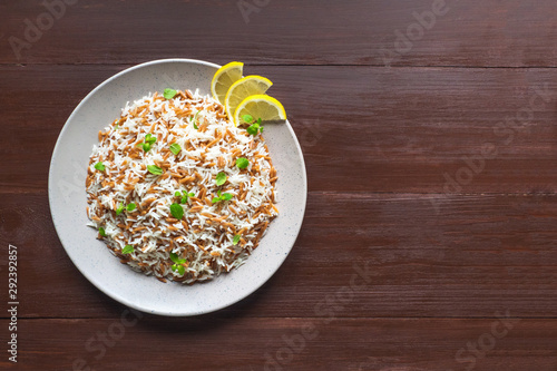 Turkish rice pilaf with orzo in a plate on a brown wooden background. Top view, copy space. 