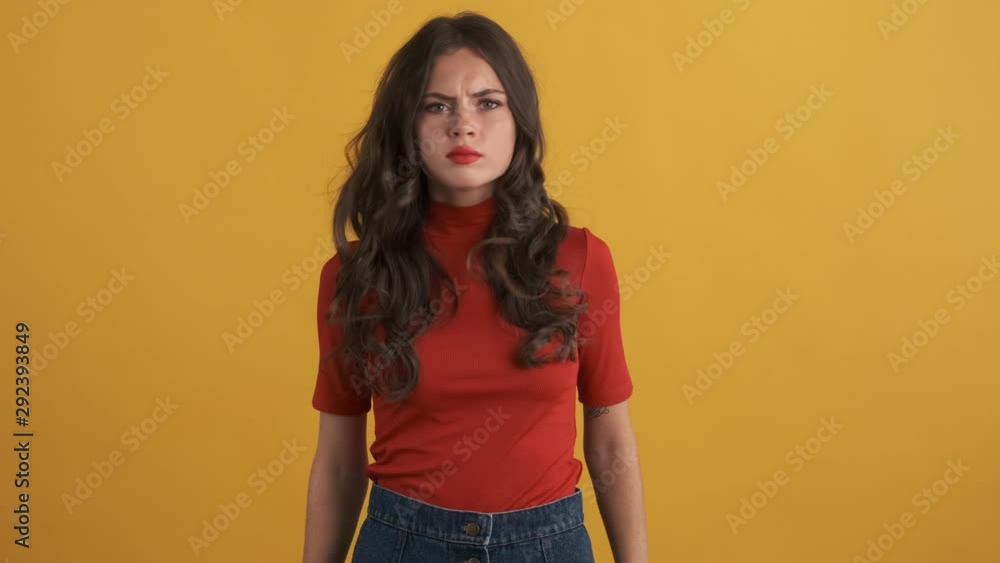 Serious brunette girl in red top angrily showing no gesture with crossed hands over yellow background Serious brunette girl in red top angrily showing no gesture with crossed hands over yellow background