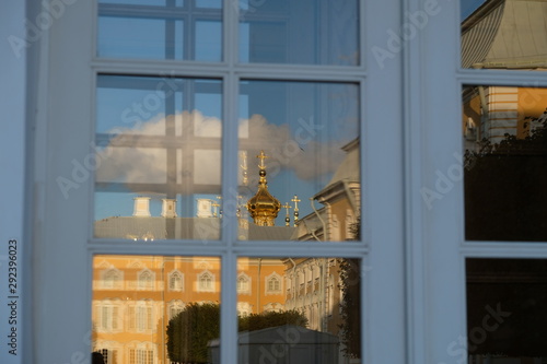 Reflection of the Orthodox Church in the window. Golden domes and crosses of the Grand Palace in Peterhof. Glitter of gold against the blue sky. Autumn sunny day.