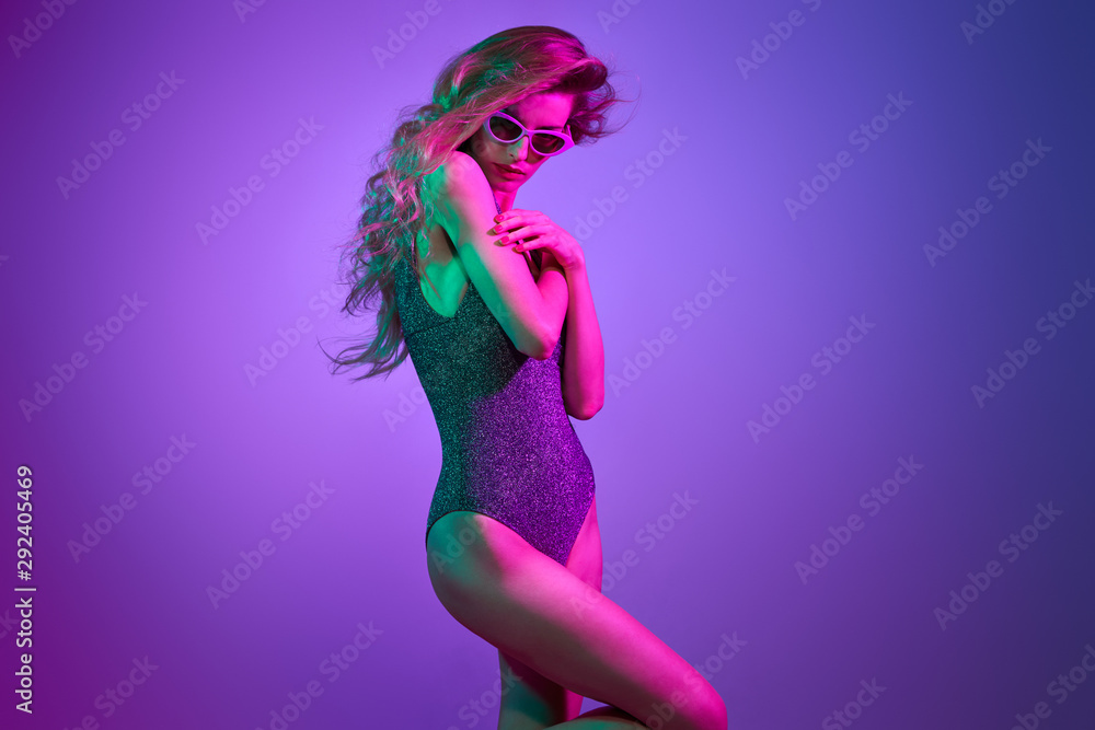 High Fashion. Party girl with pink neon hairstyle dance. Young shapely woman in Colorful uv Light. Pop Art bright fashionable creative Style. Night Club vibes. Sexy model dancing, neon purple color