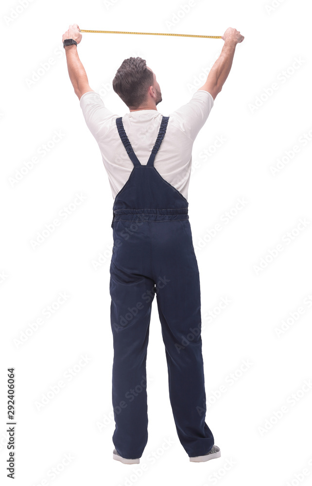 rear view. a man measuring something with a construction tape measure. rear view. a man measuring something with a construction tape measure.