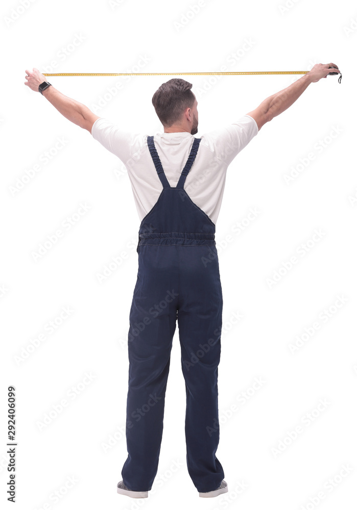 rear view. a man measuring something with a construction tape measure.