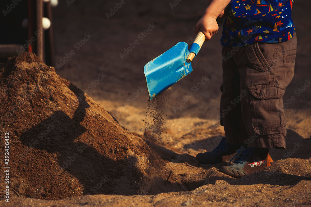 child shovels in a sandbox on a playground child shovels in a sandbox on a playground