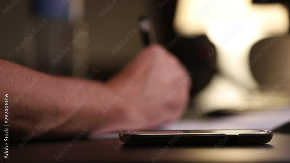 Close up young man's hand using calculator and writing at desk for conceptual purpose Close up young man's hand using calculator and writing at desk for conceptual purpose