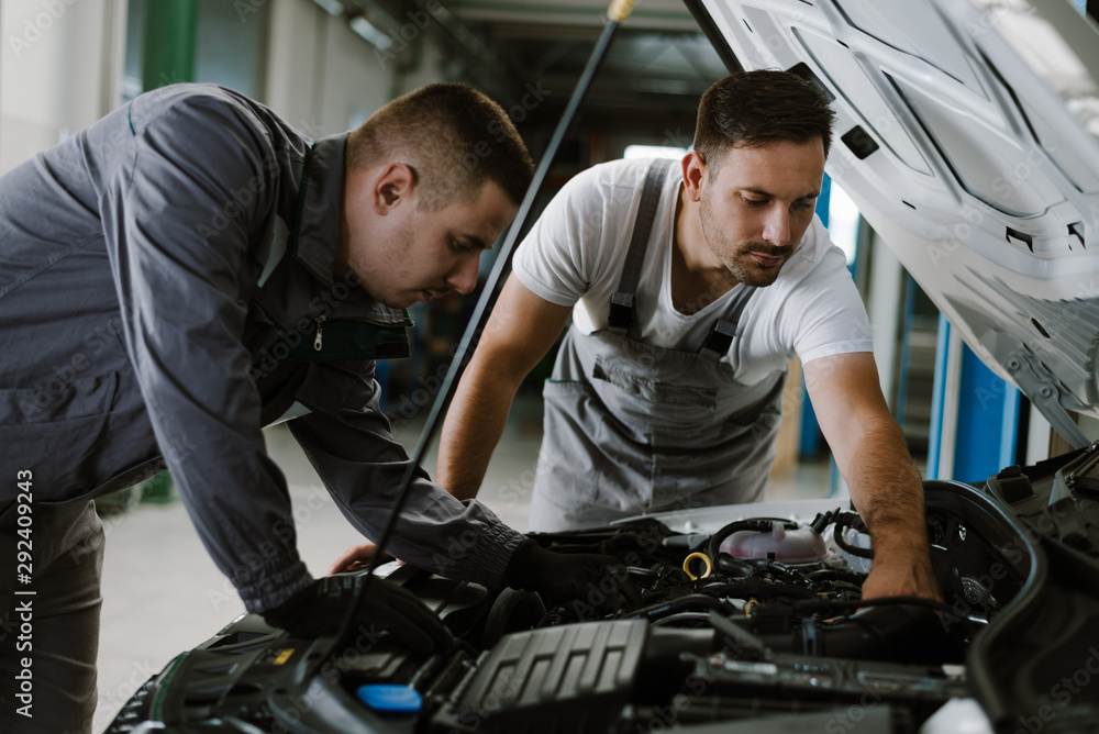 Auto mechanics working on a car engine in a workshop Auto mechanics working on a car engine in a workshop