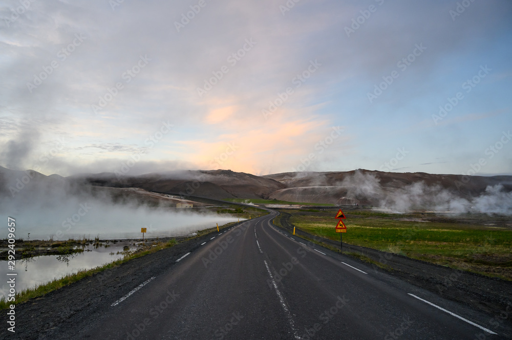 Empty road in Iceland at Hverir geothermal area with hot steam during sunset Empty road in Iceland at Hverir geothermal area with hot steam during sunset
