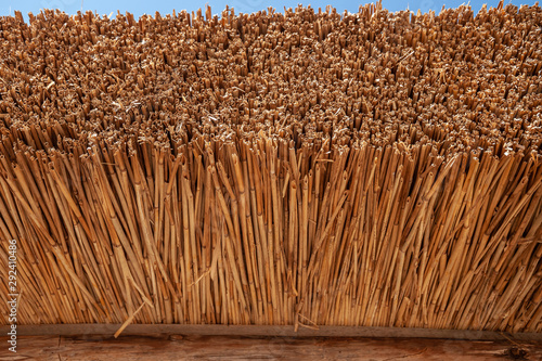 Yellow roof of a house made of straw against a blue sky.