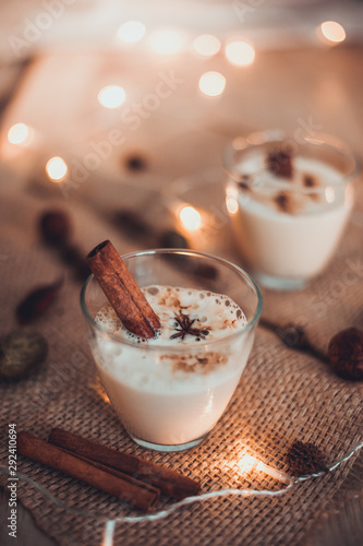 Eggnog in glasses with star anise and cinnamon on wooden table for Christmas and winter holidays. Copyspace included.