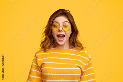 Vászonkép Amused woman in bright clothes and sunglasses looking at camera