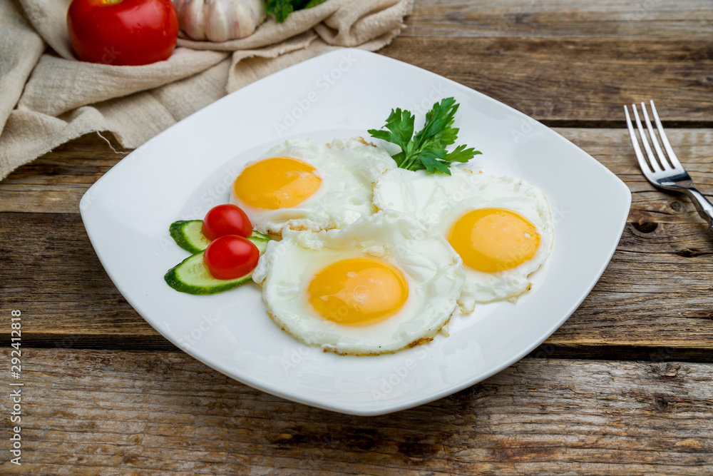 Fried eggs with tomatoes on wooden table Fried eggs with tomatoes on wooden table