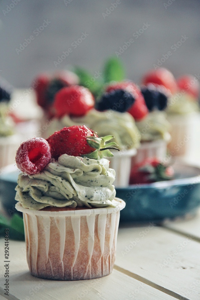 Strawberry cupcakes and green leaves on wooden background