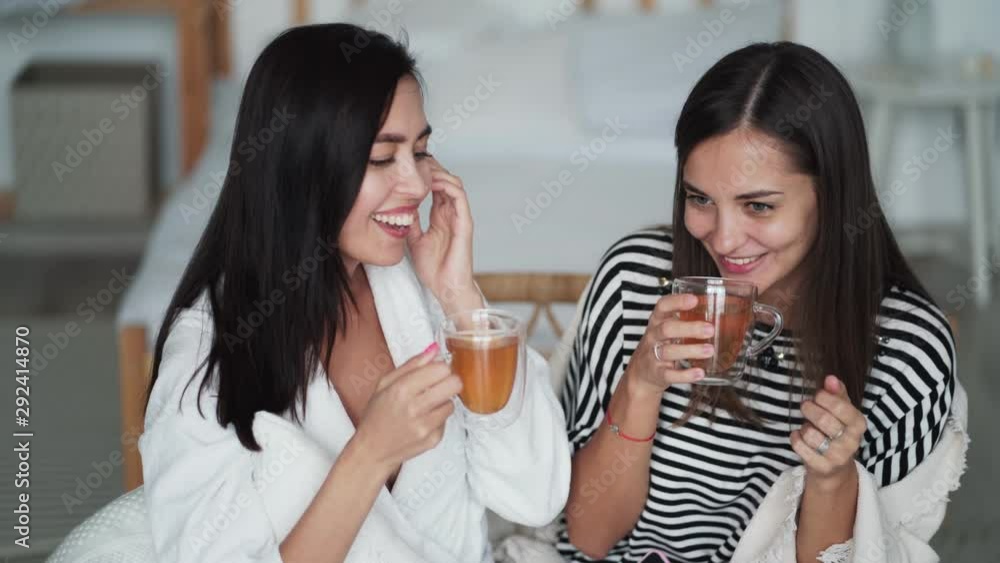 Two young beautiful women talking, smiling and drinking tea at home Two young beautiful women talking, smiling and drinking tea at home
