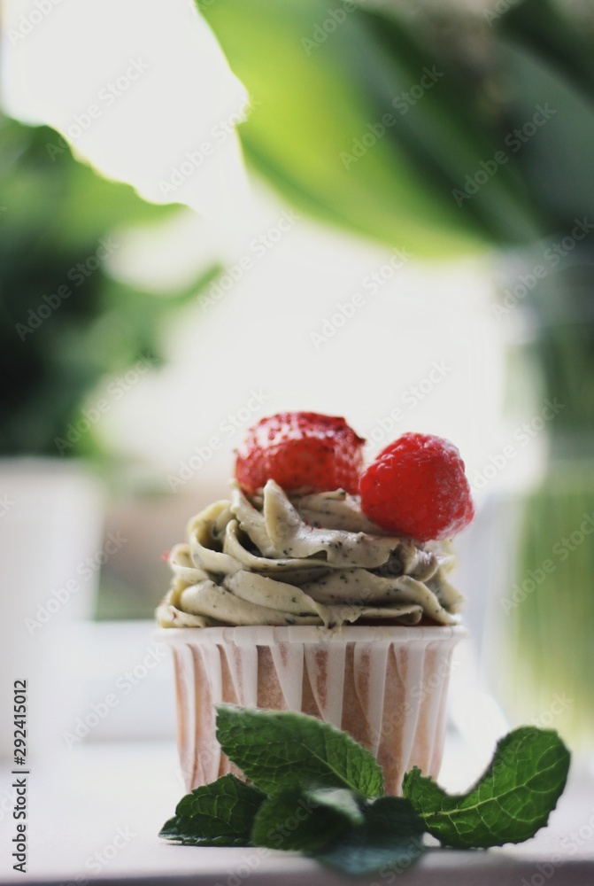 Strawberry cupcake and green leaves on wooden background