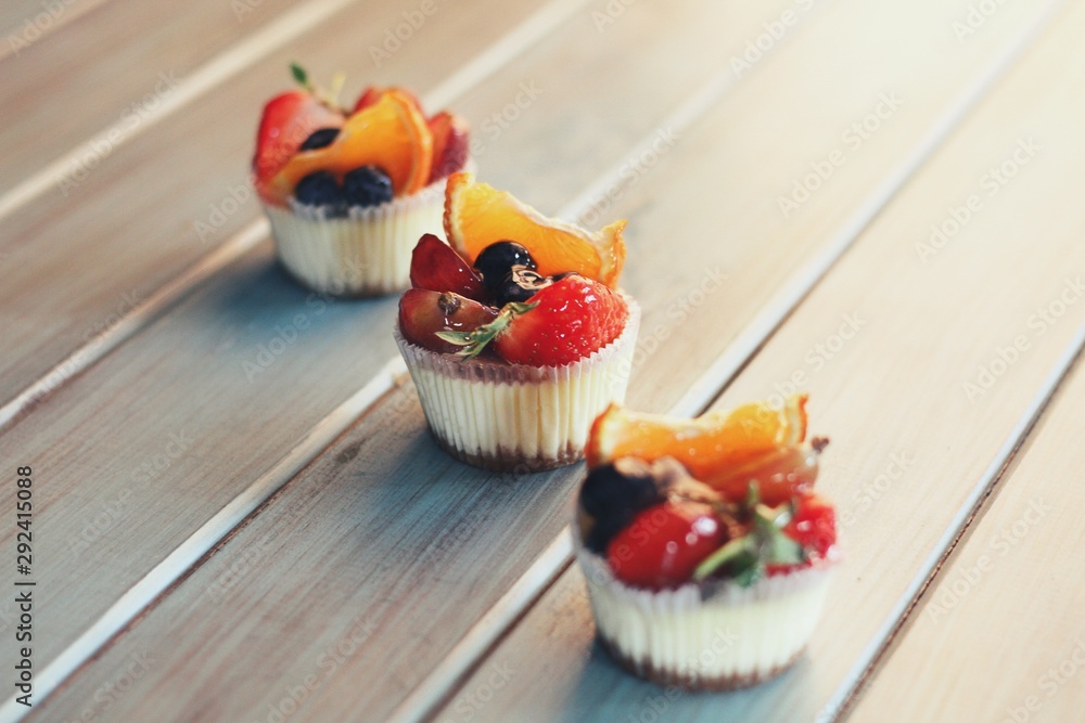 Strawberry cupcakes and green leaves on wooden background