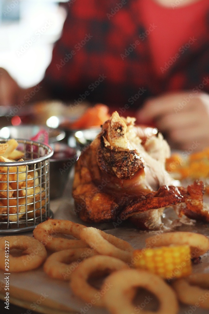 Close up of pork knuckle with snacks on pub's table background