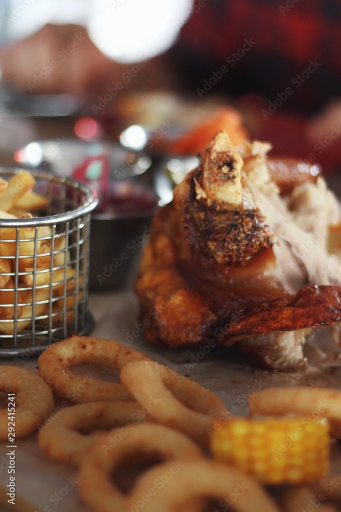 Close up of pork knuckle with snacks on pub's table background