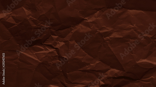 Crumpled sheet of dark brown paper texture. Creased background