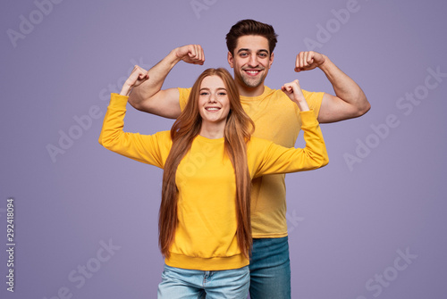 Cheerful young couple flexing muscles photo